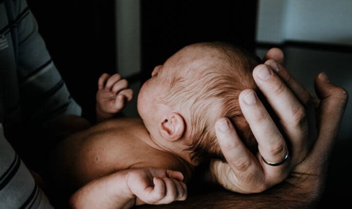 A newborn baby being held by an adult