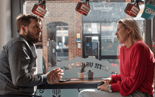 A woman and a man sitting at a cafe table discussing business
